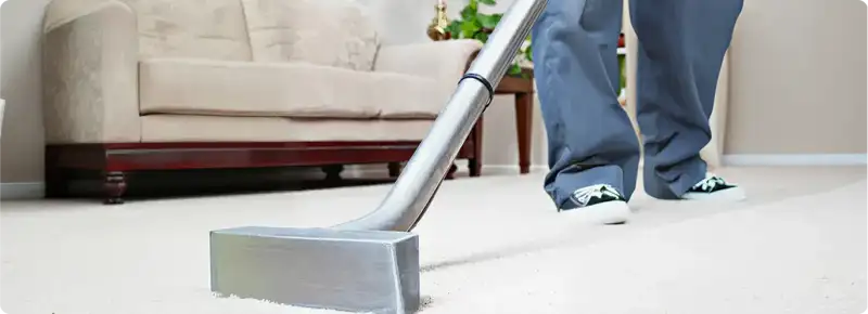 Carpet cleaning technician using a hot-water extraction wand on a light-colored carpet in a living room, Las Vegas, NV.