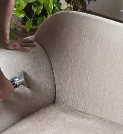 Professional upholstery cleaner deep-cleaning a fabric sofa with a handheld extraction tool and hose Las Vegas, NV.
